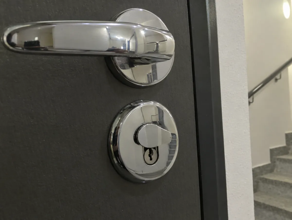 Escudo protector de acero alrededor del bombín en una puerta de entrada