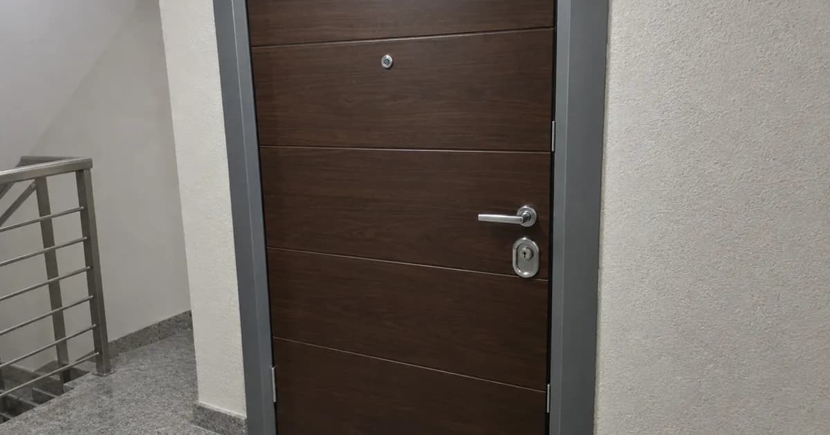 Puerta acorazada con panel de madera en el rellano de un edificio de viviendas