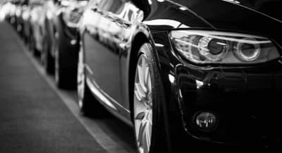 Frontal de un coche negro aparcado en una fila de vehículos