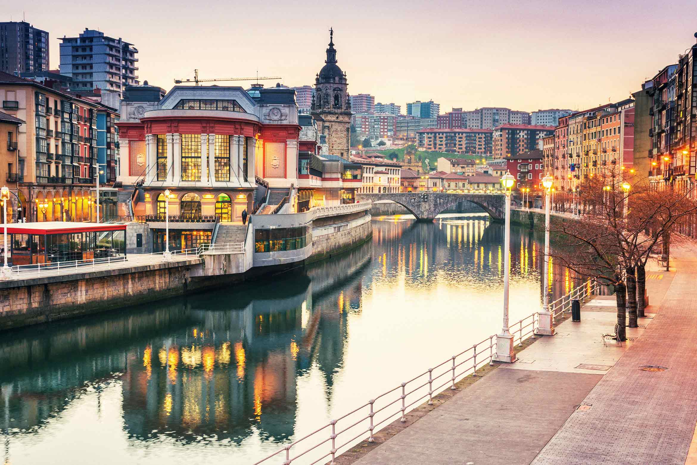 La ría de Bilbao al atardecer con el paseo y los edificios iluminados