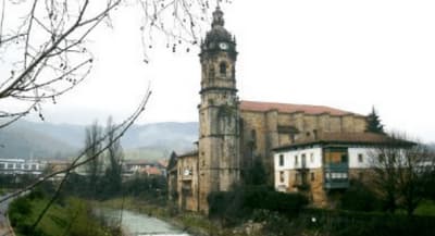 Iglesia de piedra con torre campanario junto al río en Amorebieta