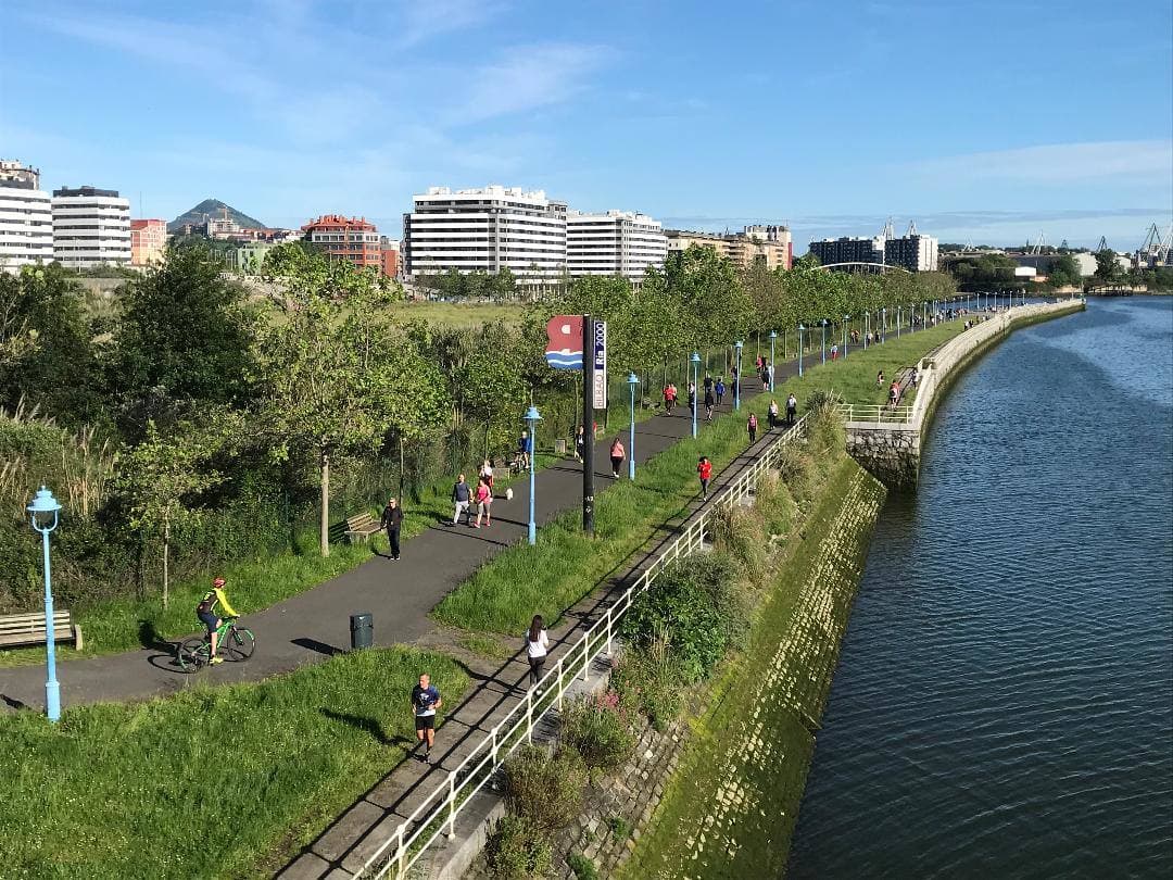 Paseo de bidegorri junto a la ría en Barakaldo con edificios de viviendas al fondo
