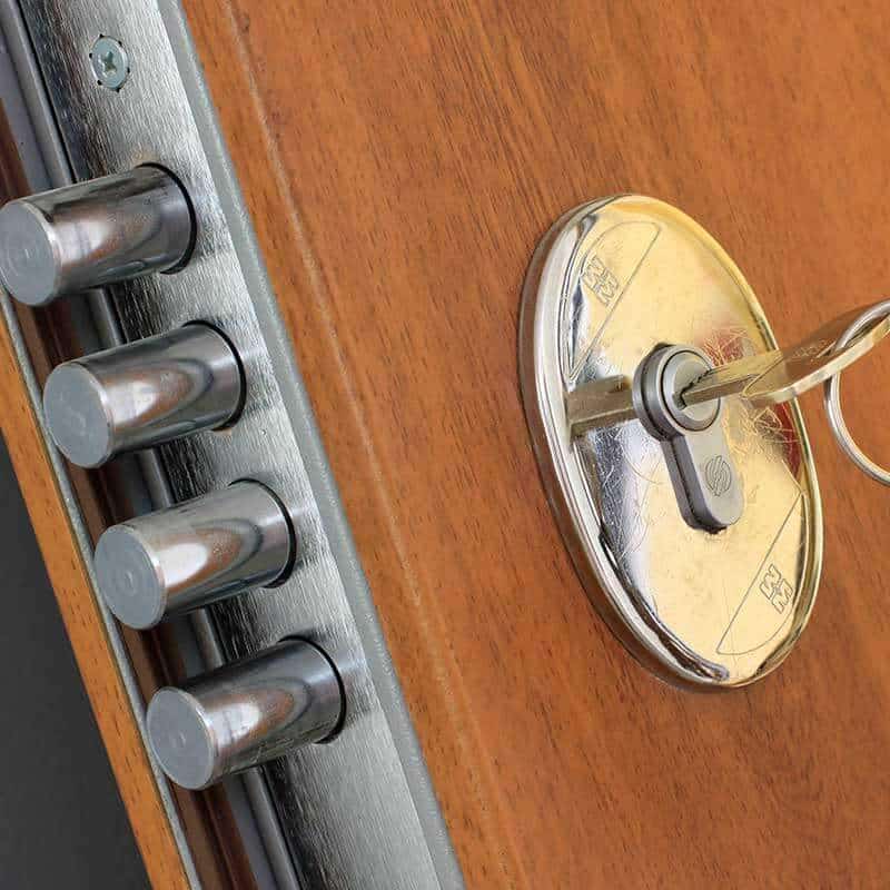 Canto de una puerta de madera con cerradura de varios bulones y la llave en el bombín