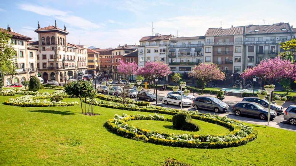Jardines con árboles en flor frente a edificios del centro de Gernika